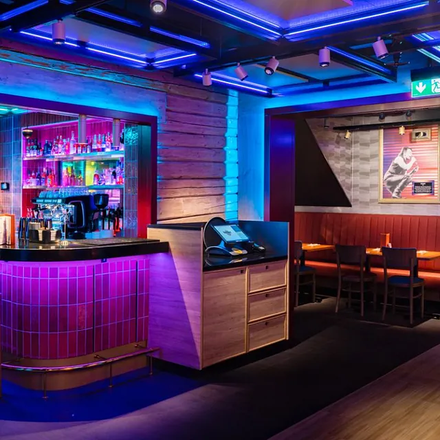 Restaurantinteriør med bar, sitteplasser og fargerik belysning