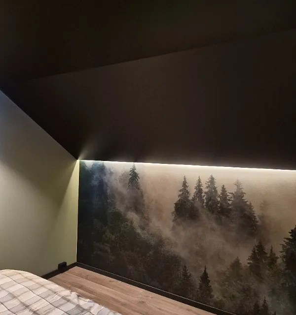 Soverom med skråtak og veggdekor av skogmotiv